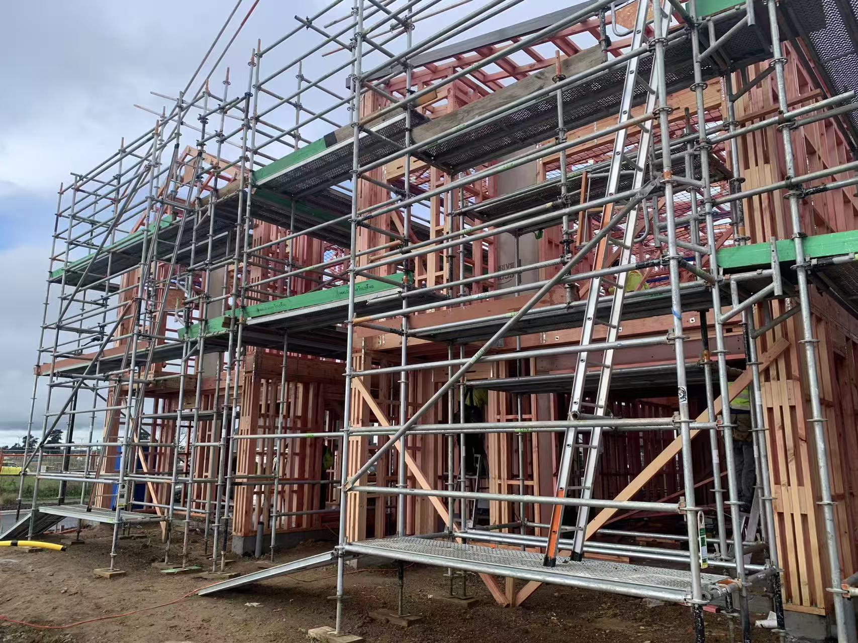 Timber-framed houses under construction with exterior scaffolding