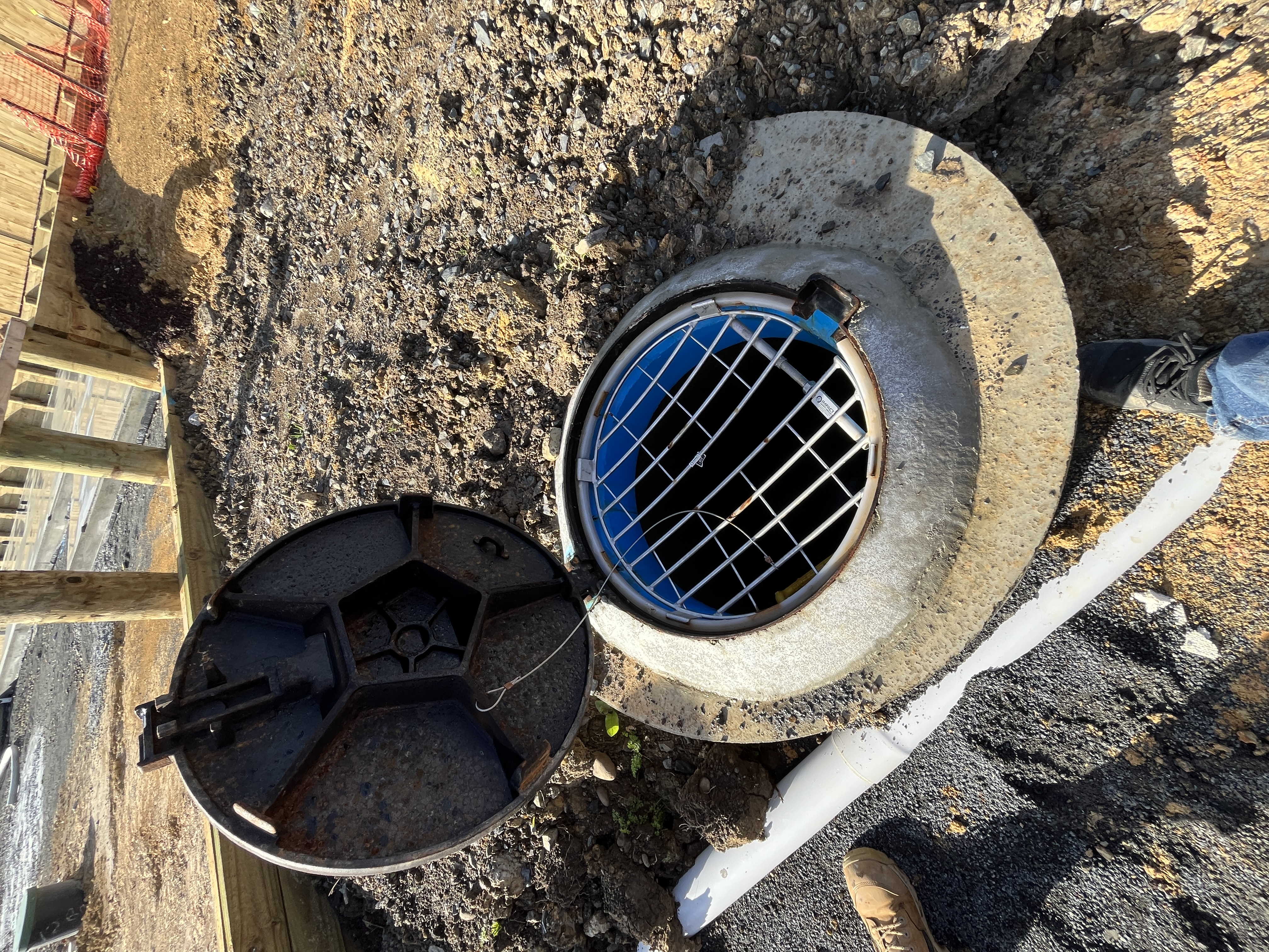 Installed drainage manhole with cover open and safety grille